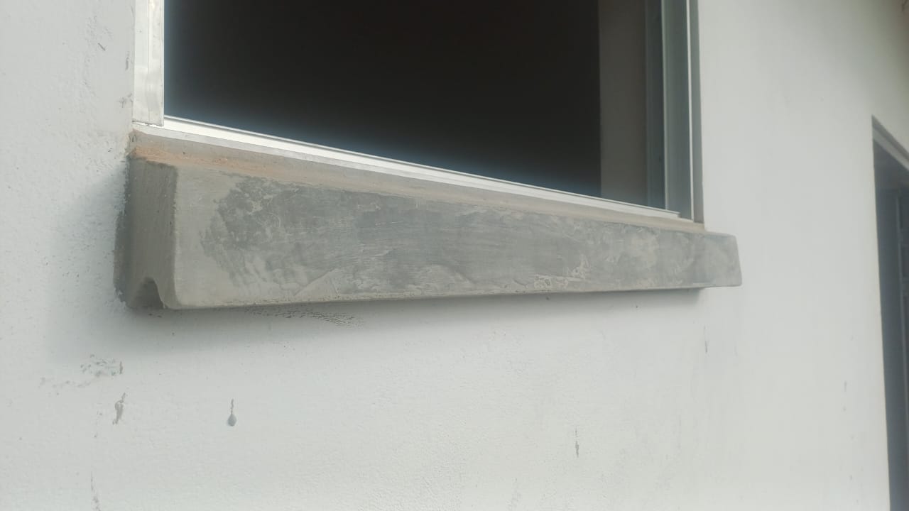 Detalle de alfeisar en concreto bajo ventaneria de aluminio